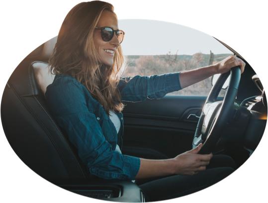 A smiling young woman keeps her eyes on the road.